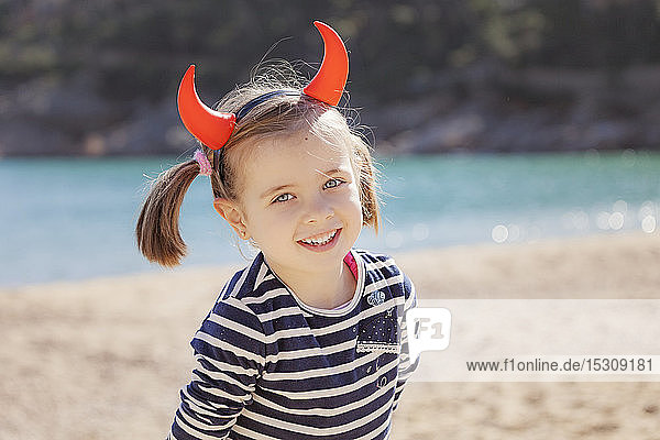 Portrait of girl on the beach wearing devil's horns