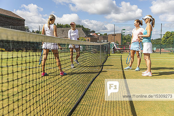 Reife Frauen unterhalten sich auf dem Rasenplatz des Tennisclubs