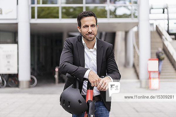 Portrait of businessman with e-scooter in the city