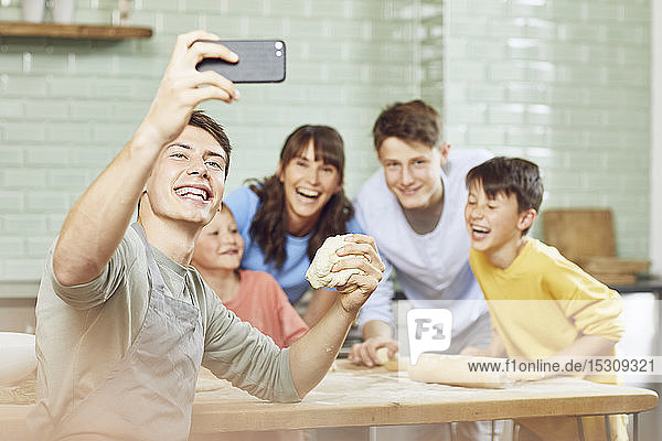 Sone taking pictures of his mother and brothers  preparing pizza at home