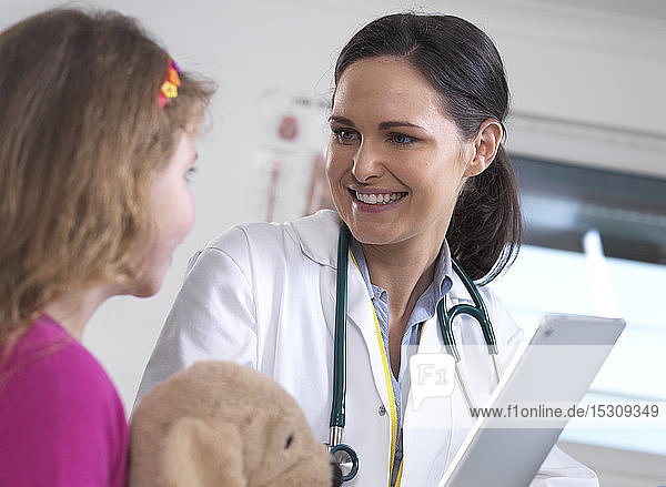 Ärztin zeigt einer jungen Patientin in der Klinik ihre Laborergebnisse auf einem digitalen Tablett