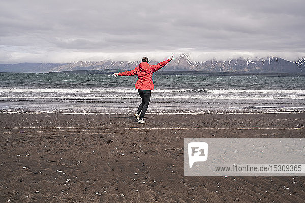 Junge Frau tanzt am Lavastrand am Eyjafjordur-Fjord  Island
