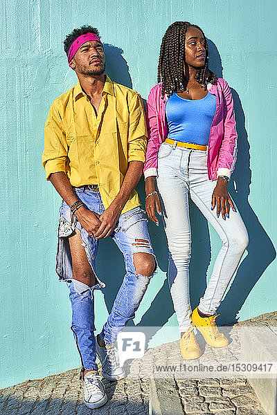 Young black lovers posing in front of a blue wall