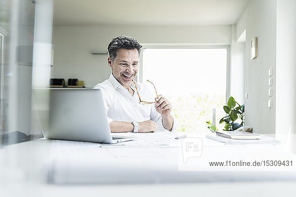 Architect sitting in bright office using laptop