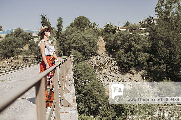 Porträt eines lächelnden jungen Mädchens mit Strohhut  auf einer Brücke stehend