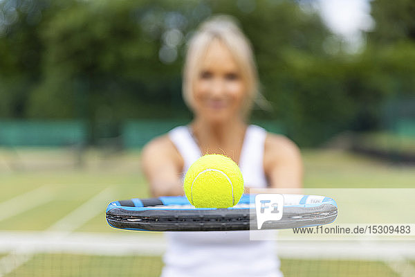 Nahaufnahme einer Frau  die im Tennisclub einen Tennisschläger mit einem Ball in der Hand hält