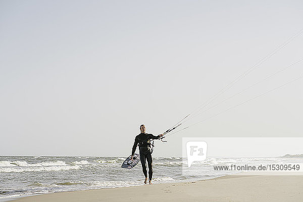 Kiteboarder geht mit seinem Drachen am Strand