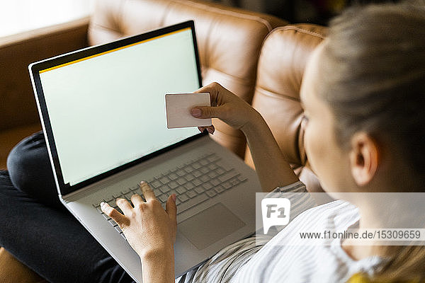Junge Frau auf der Couch zu Hause beim Online-Shopping