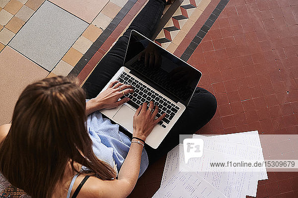 Female student studying at home  using laptop  from above