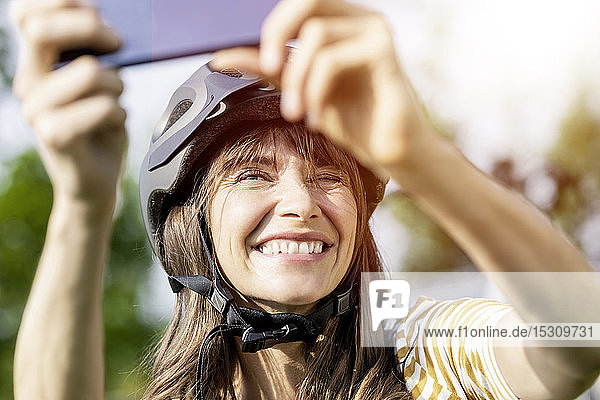 Glückliche Frau mit Fahrradhelm beim Selfie