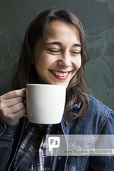 Young laughing woman in cafe with cup of coffee and looking sideways