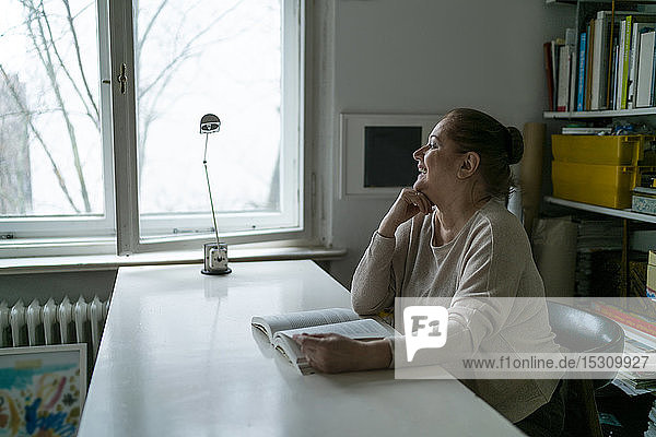 Happy senior woman reading book at home