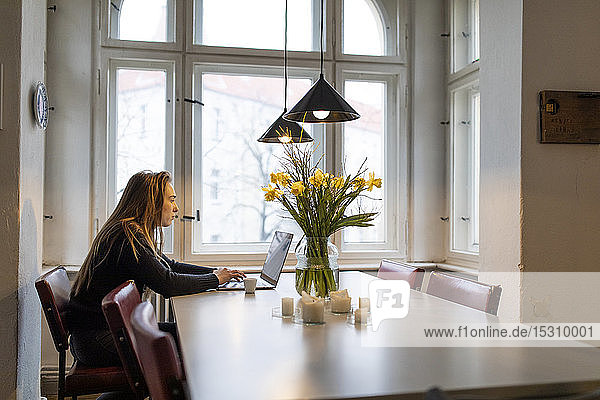 Young woman using laptop on table at home