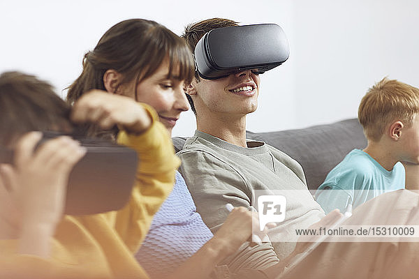 Happy family sitting on couch  using VR goggles and mobile devices