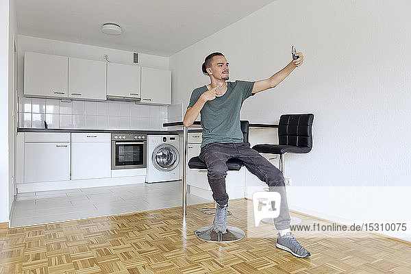 Young man taking a selfie with his smartphone in an empty apartment