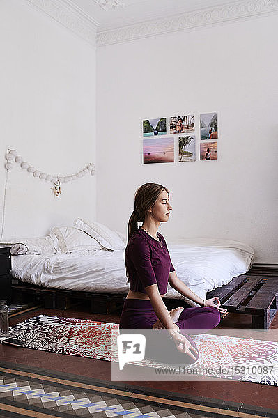 Junge brünette Frau praktiziert Yoga im Studentenwohnheim
