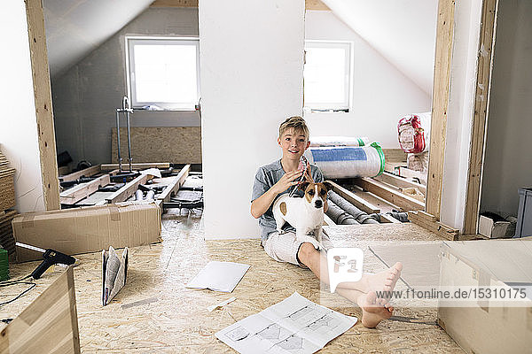 Porträt eines lächelnden Jungen mit Hund in einem zu renovierenden Haus
