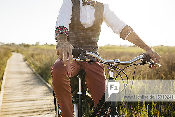 Gut gekleideter Mann mit seinem Fahrrad auf einem Holzsteg auf dem Land nach der Arbeit
