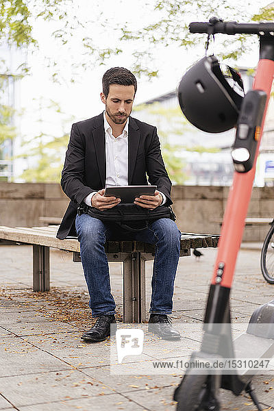 Geschäftsmann mit E-Scooter mit Tablet in der Stadt