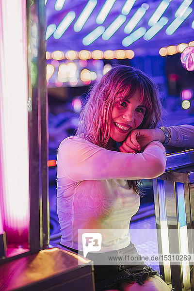 Portrait of a smiling young woman on a funfair at night
