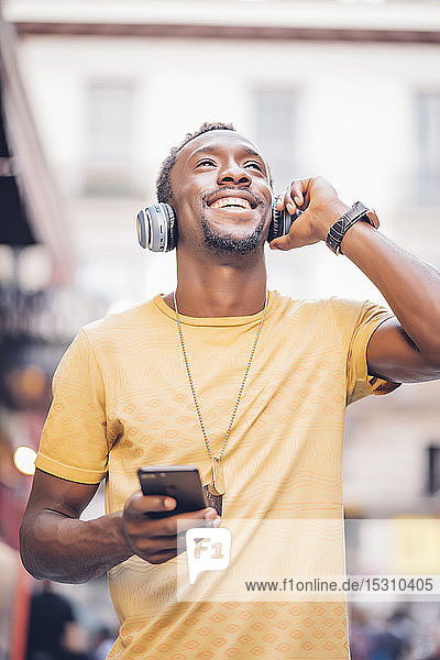 Porträt eines glücklichen Mannes  der mit Kopfhörer und Smartphone Musik hört
