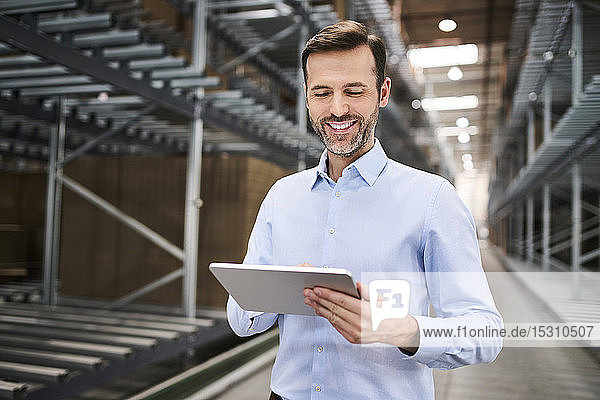 Smiling businessman using tablet in a factory