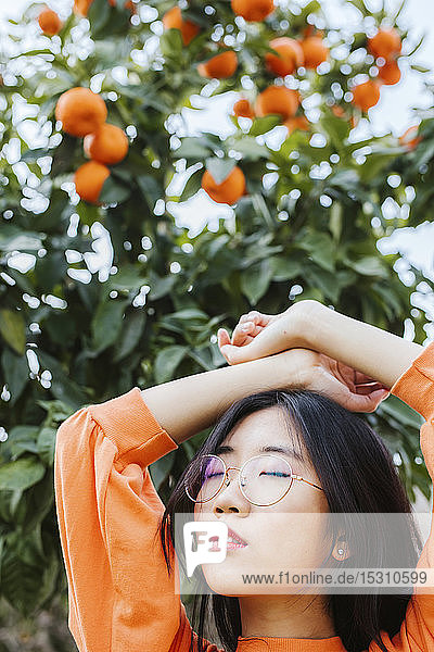 Porträt einer jungen Asiatin  im Hintergrund ein Mandarinenbaum