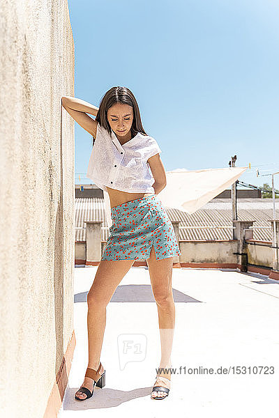 Fashionable young woman leaning at wall on roof top