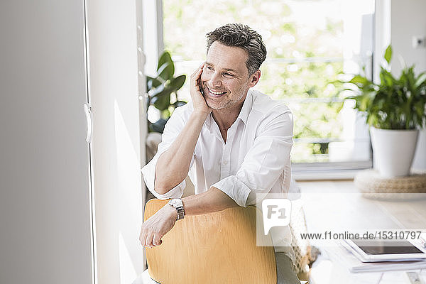 Mature man sitting on chair backwards smiling