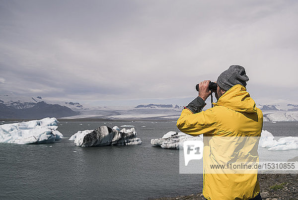 Erwachsener Mann beobachtet den Vatnajokull-Gletscher mit dem Fernglas  Island