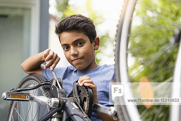 Porträt eines selbstbewussten Jungen  der sein Fahrrad repariert