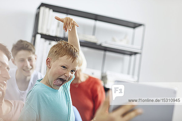 Kleiner Junge sieht sich mit seiner Familie ein digitales Tablet an