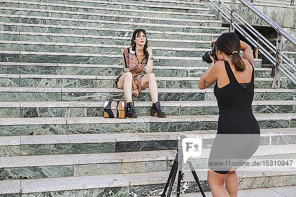 Junge Frau in gemustertem Kleid posiert für ein Fotoshooting auf einer Treppe