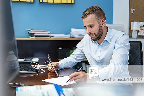 Businessman with papers and tablet at desk in office