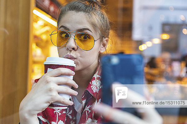 Junge Frau in einem Café  die sich beim Kaffeetrinken ein Selfie gönnt