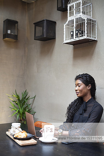 Schicke Geschäftsfrau mit Laptop am Tisch in einem Cafe