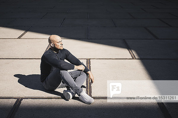 Mann macht Pause im Sonnenlicht sitzend