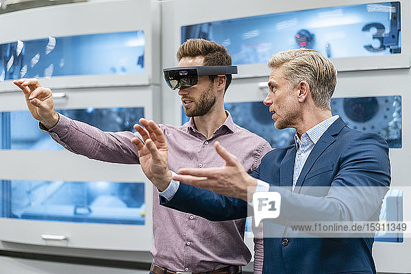 Two businessmen with AR glasses in a modern factory