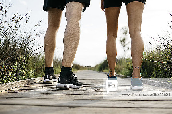 Rear view of joggers standing on wooden walkway