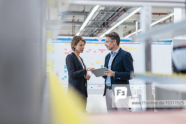 Businessman and businesswoman talking in a factory hall