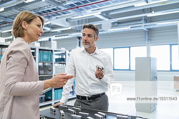Businessman and businesswoman talking in a modern factory hall
