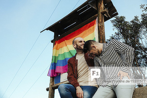 Glückliches schwules Paar mit der Gay-Pride-Flagge auf einer Reise