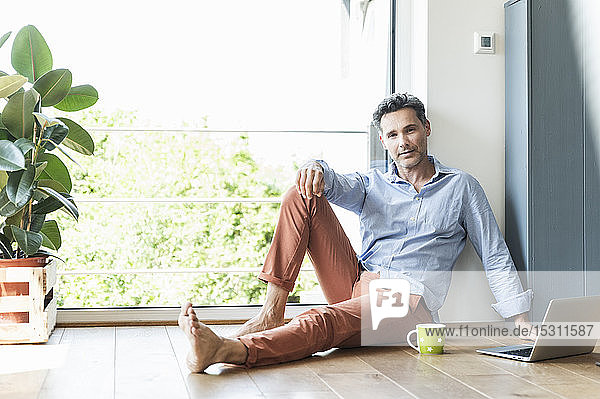 Mature man relaxing at home with a cup of coffee  using laptop
