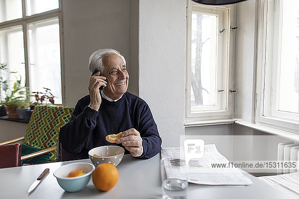 Lächelnder älterer Mann am Handy zu Hause