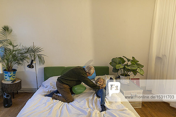Glücklicher Großvater spielt mit seinem Enkel zu Hause im Bett