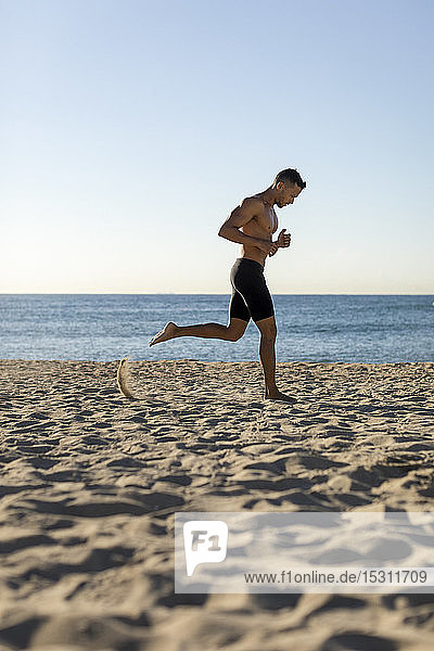 Barbrüstiger Mann joggt am Strand