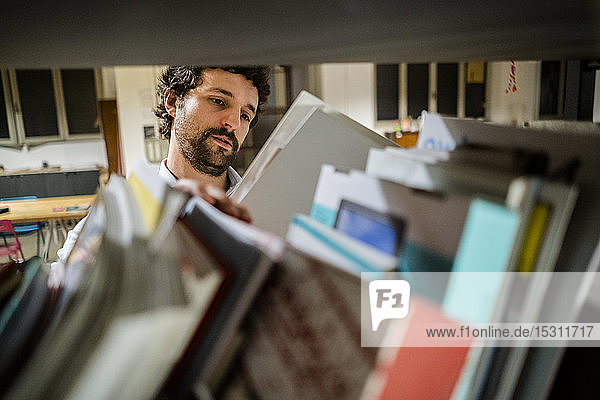 Businessman reading file at shelf in office