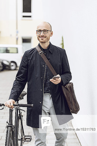 Mann mit Fahrrad geht mit seinem Smartphone zur Arbeit
