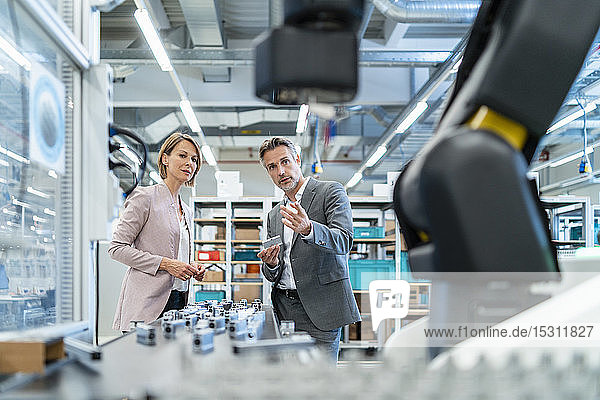 Businessman and businesswoman talking in a modern factory hall