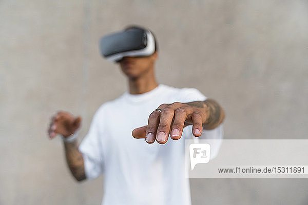 Hand eines tätowierten jungen Mannes mit einer Virtual-Reality-Brille  Nahaufnahme